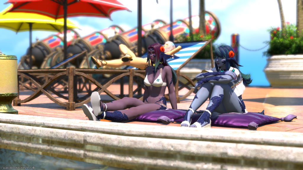 Lizicus and Laureine sitting on the edge of a pool in their swimwear.