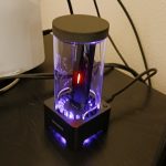 An M.2 SSD docking station attached to the back of a Playstation 5 with blue lights and the M.2 itself glowing an amber light.