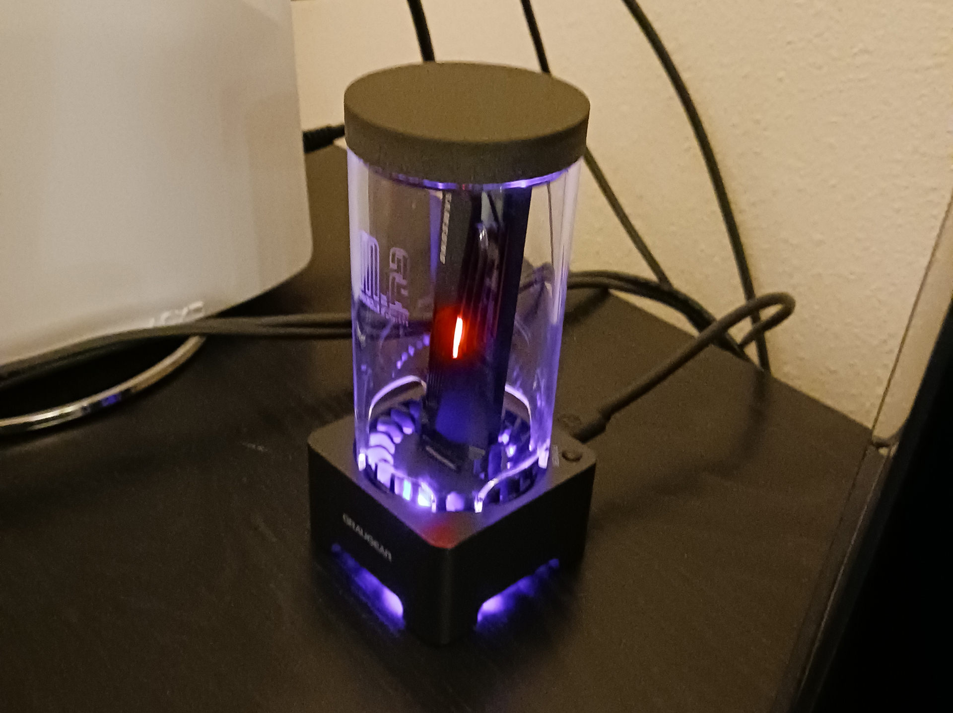 An M.2 SSD docking station attached to the back of a Playstation 5 with blue lights and the M.2 itself glowing an amber light.
